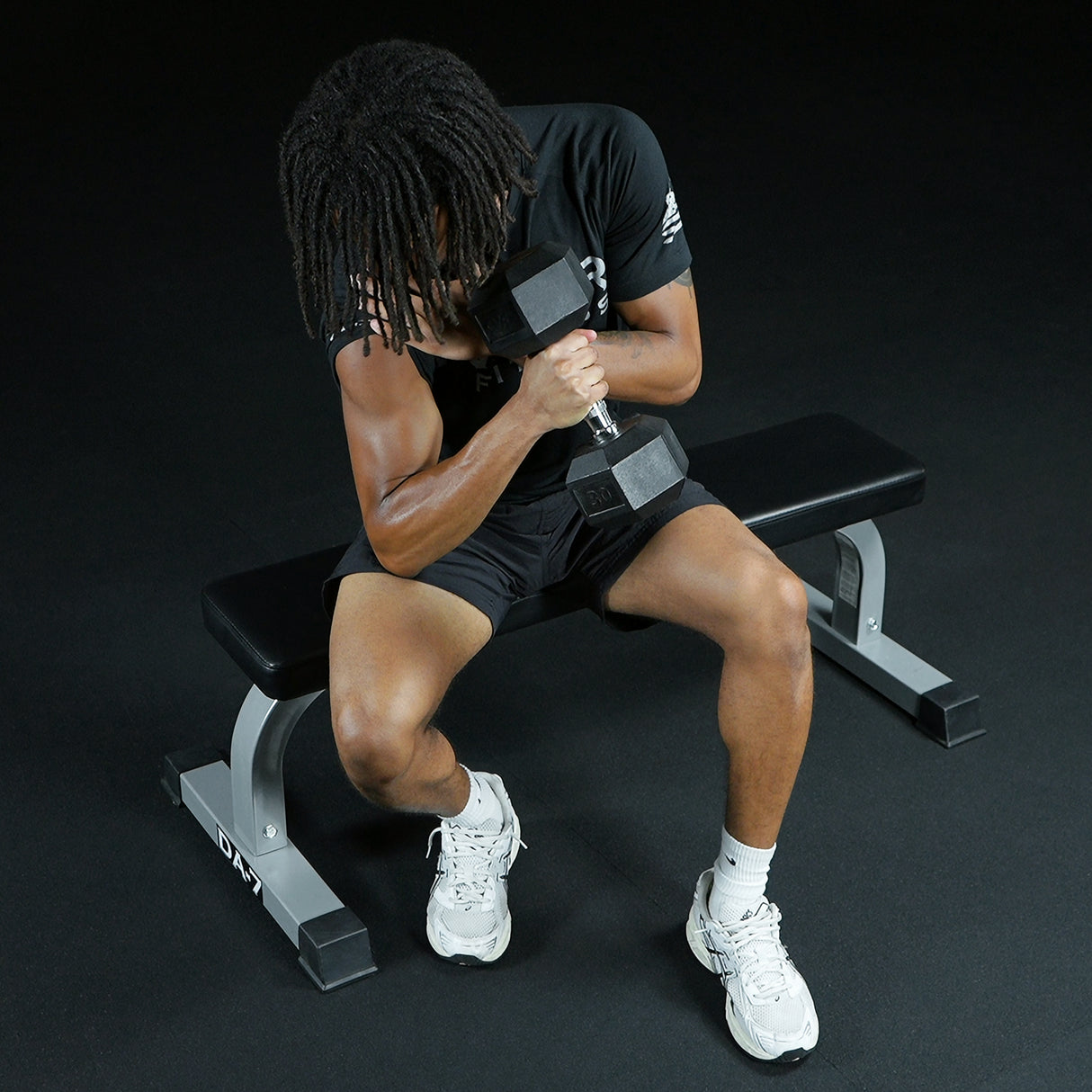 Single arm dumbbell curls while sitting on a flat bench