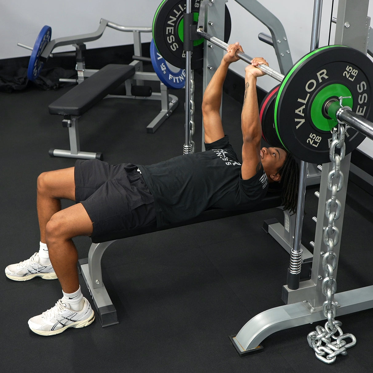 Person performing a bench press with a smith machine in a gym setting