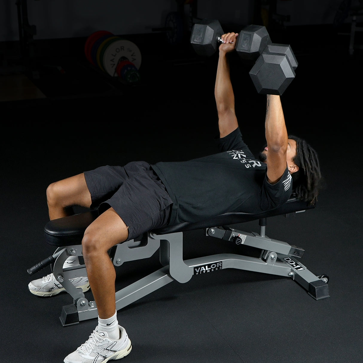 Person performing bench press with dumbbells on a Valor Fitness bench.