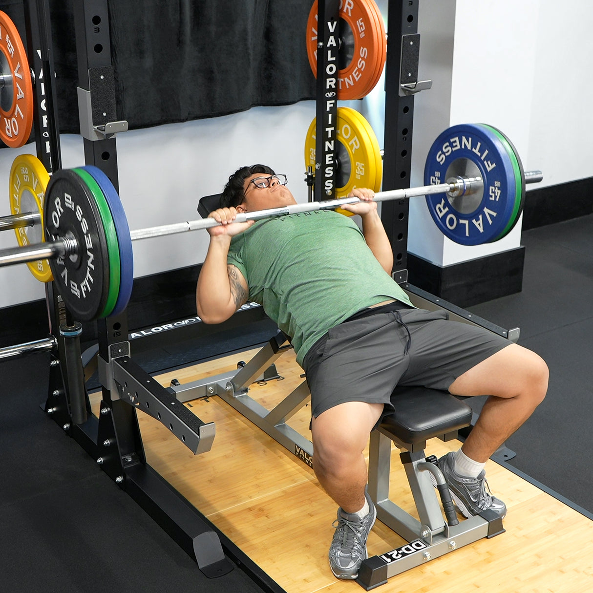 Bench press exercise with a Valor Fitness barbell, plates, and 3x3 half rack