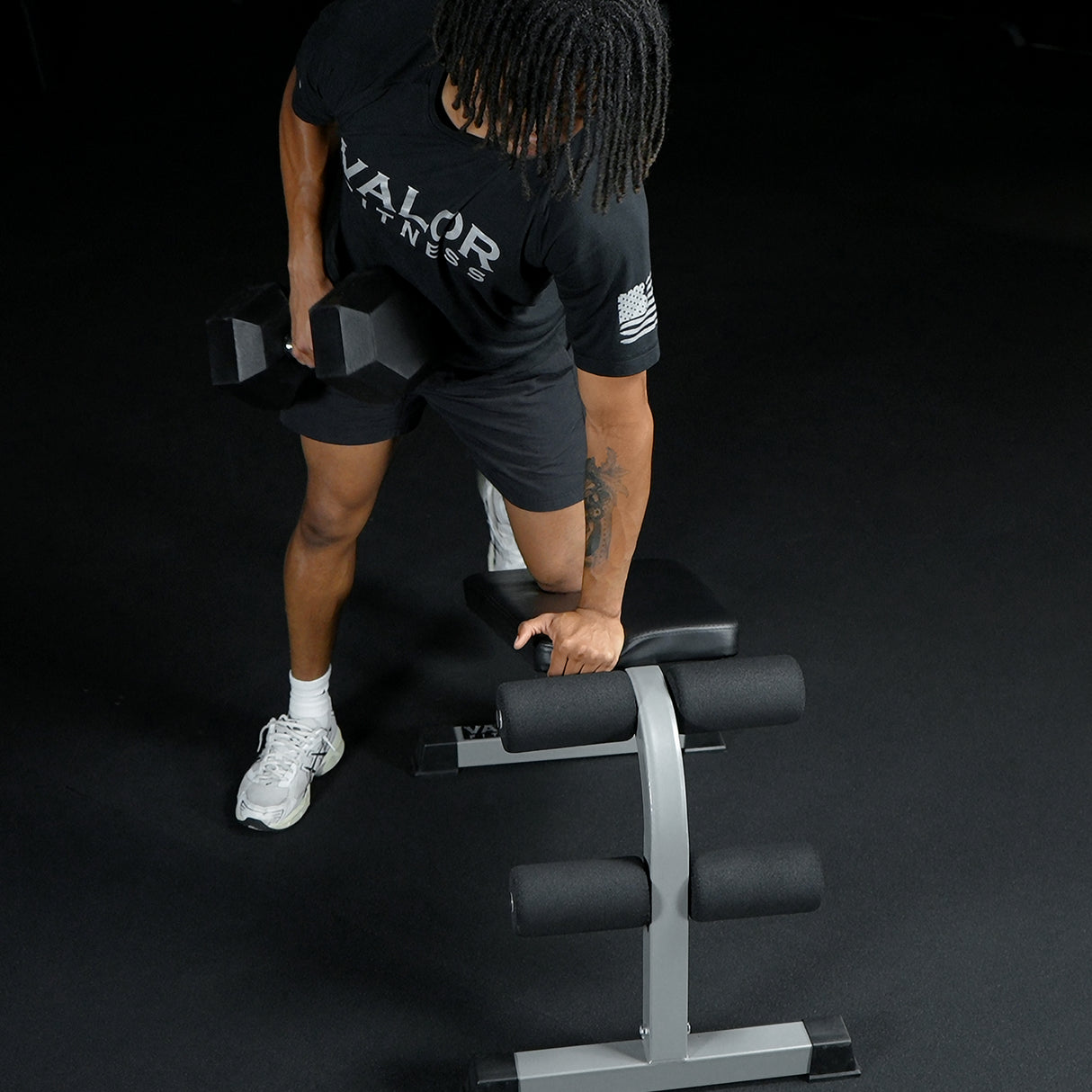 Leaning on a sit-up weight bench to do single arm dumbbell bent rows
