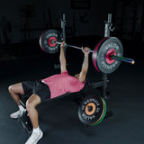 Person exercising a bench press with barbell and Valor Fitness weights in a gym setting