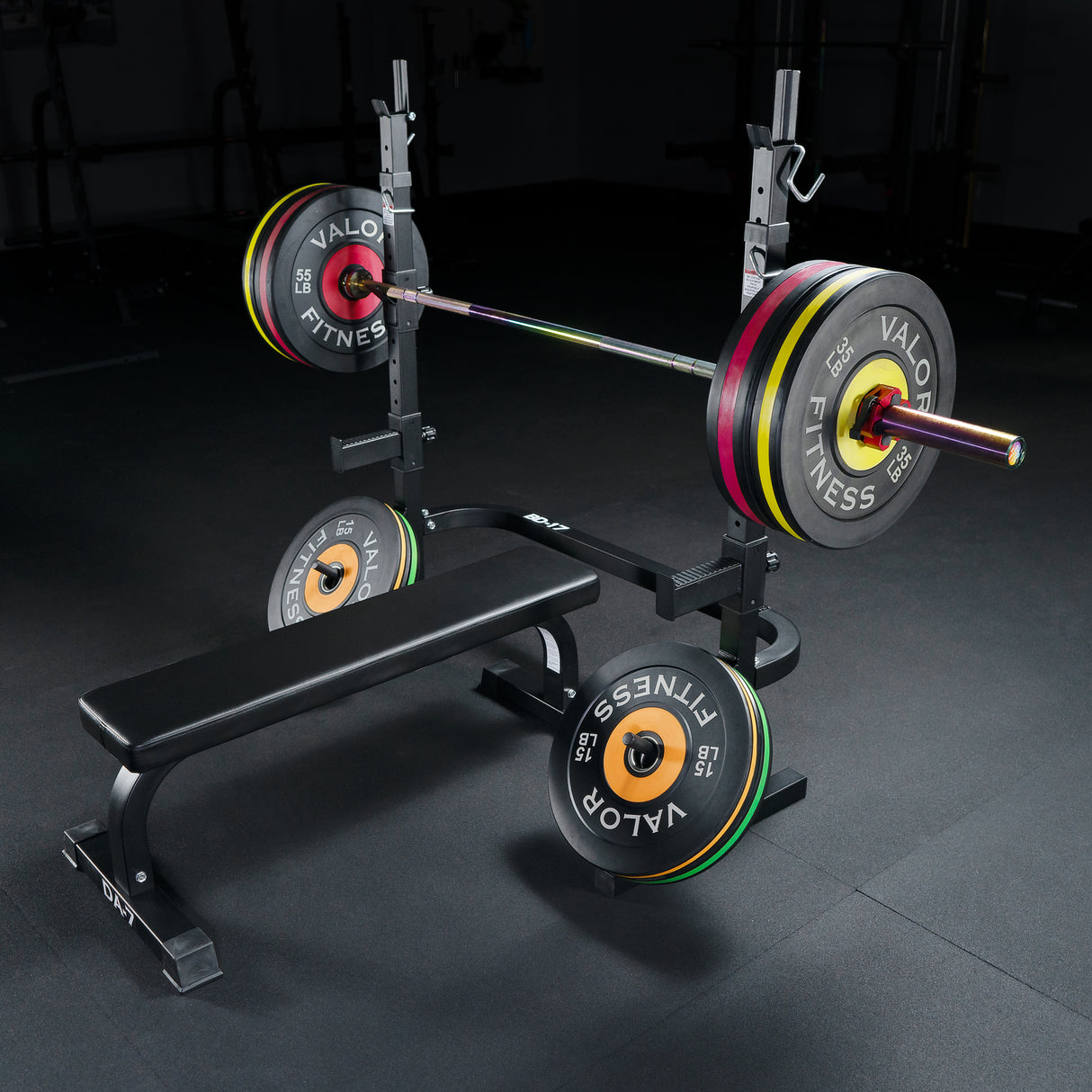 Barbell with weight plates on a bench and squat rack in a gym setting