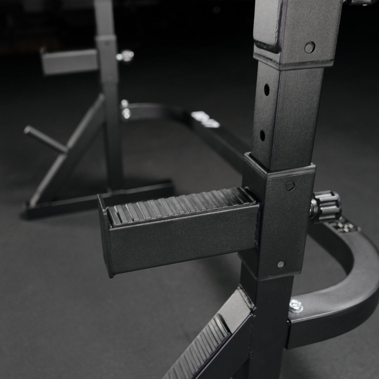 Close up of textured rubberized safety catches on home gym squat and bench rack