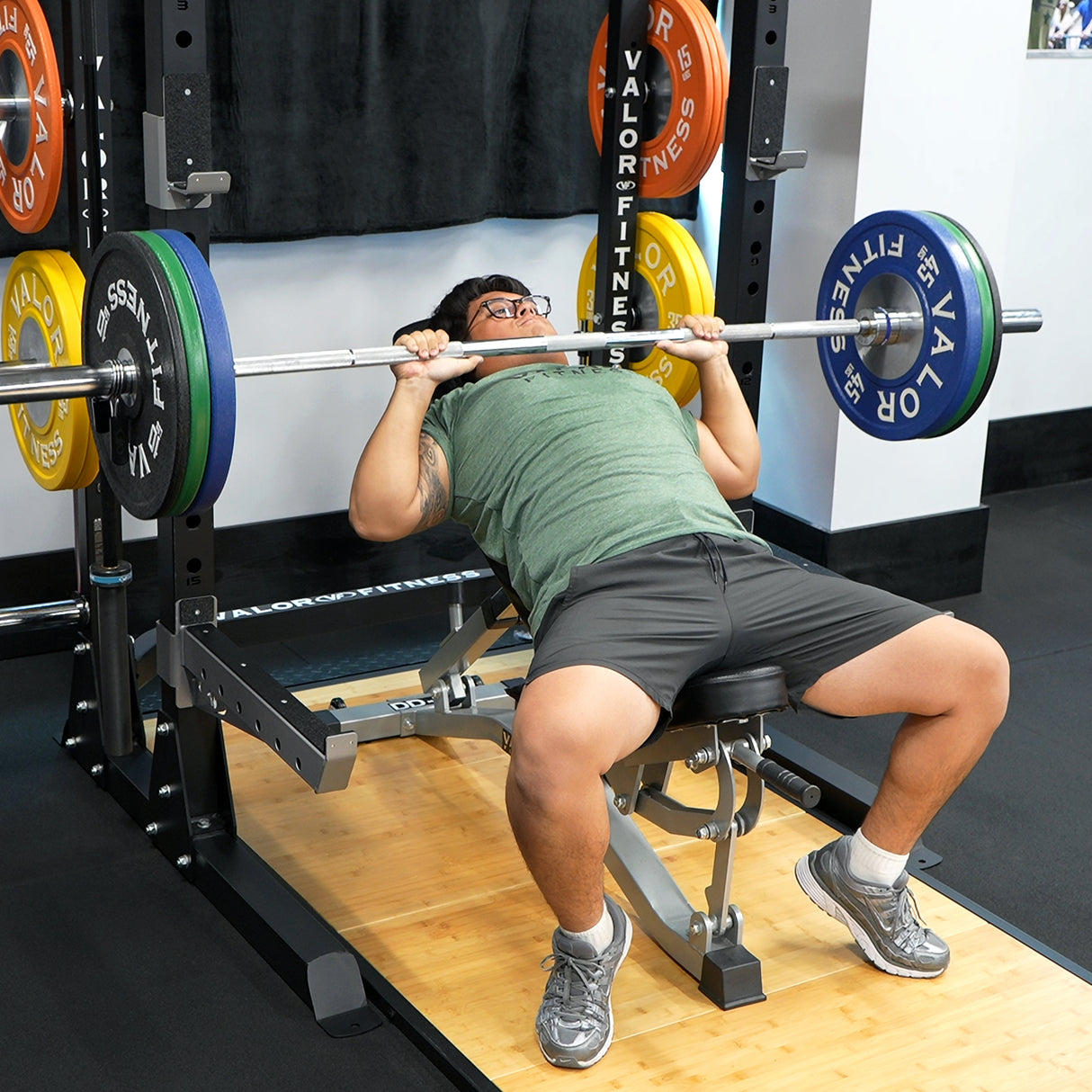 Person performing a bench press with a barbell and performance half rack