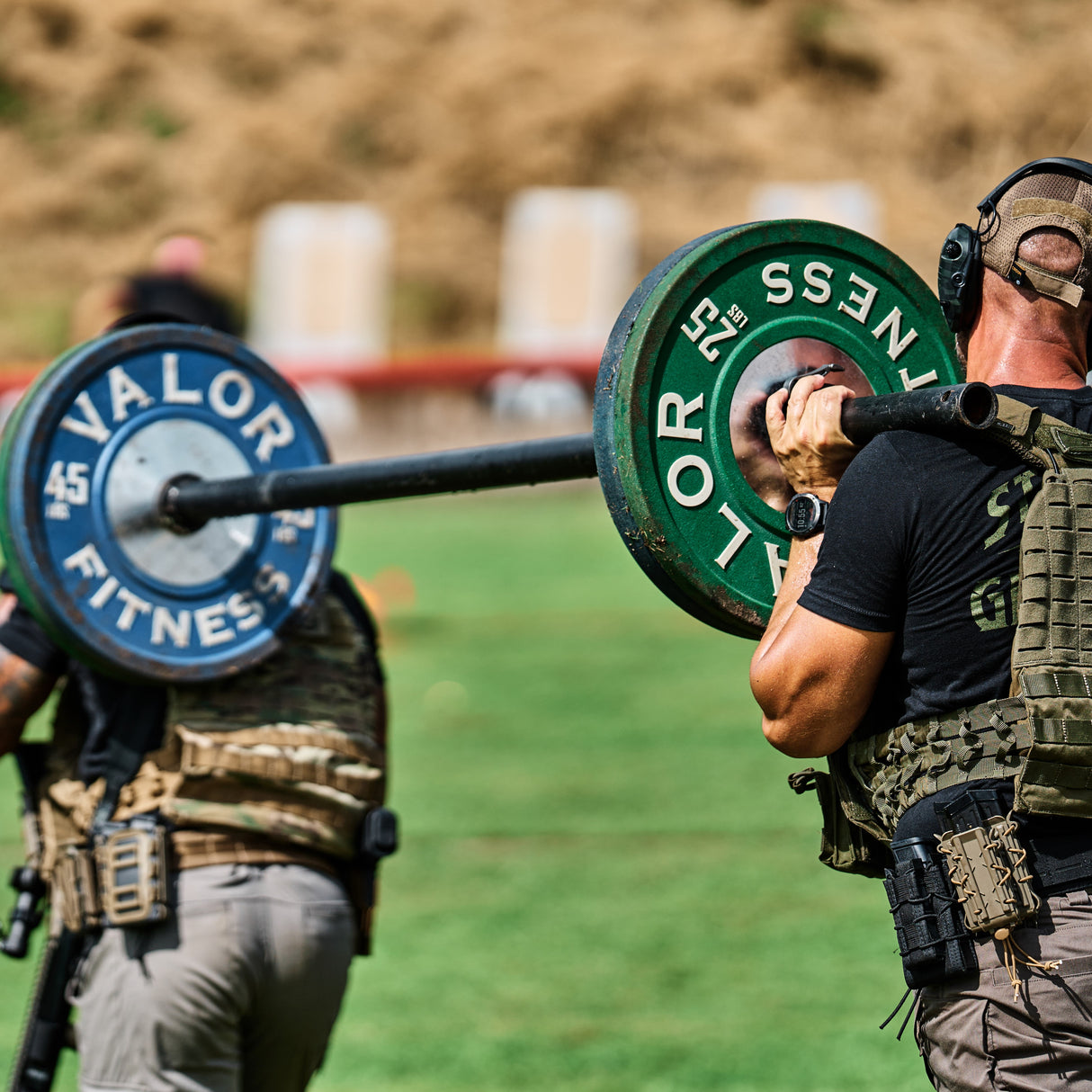 Two athletes doing a shoulder carry with a strongman fat barbell